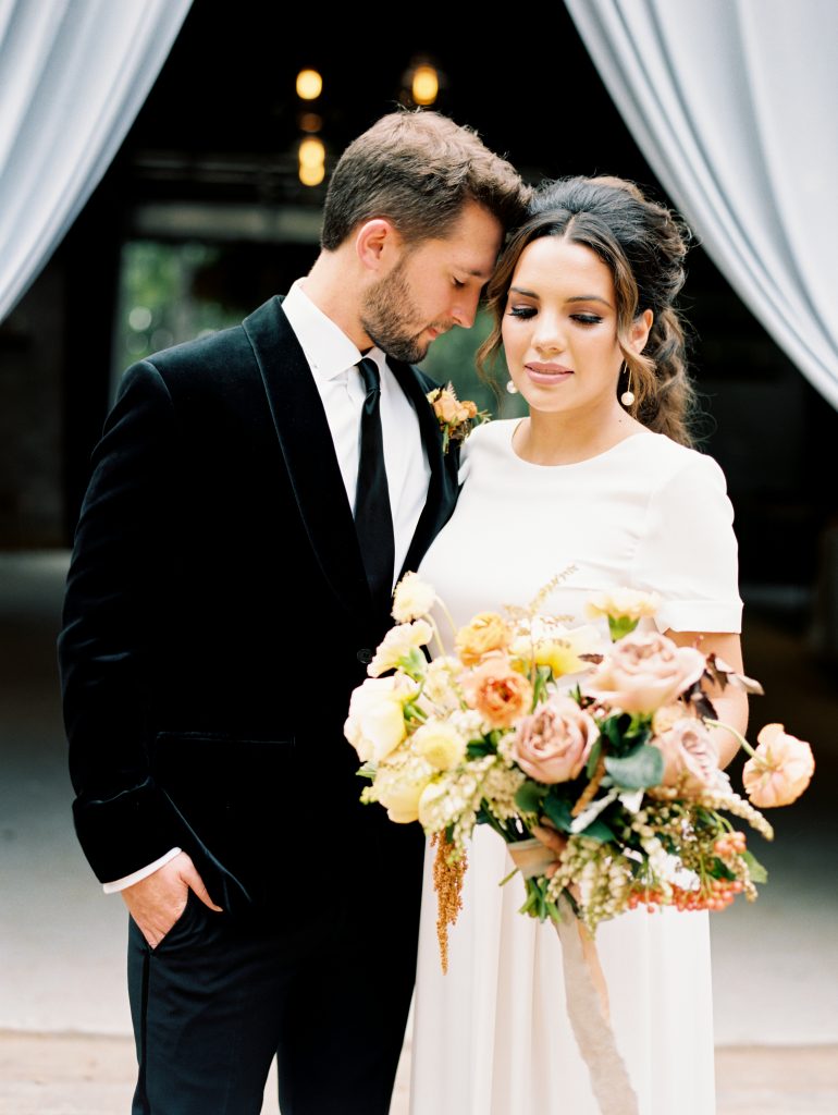 The bride and groom wear velvety warm fall style decorated with rustic colors and textures.